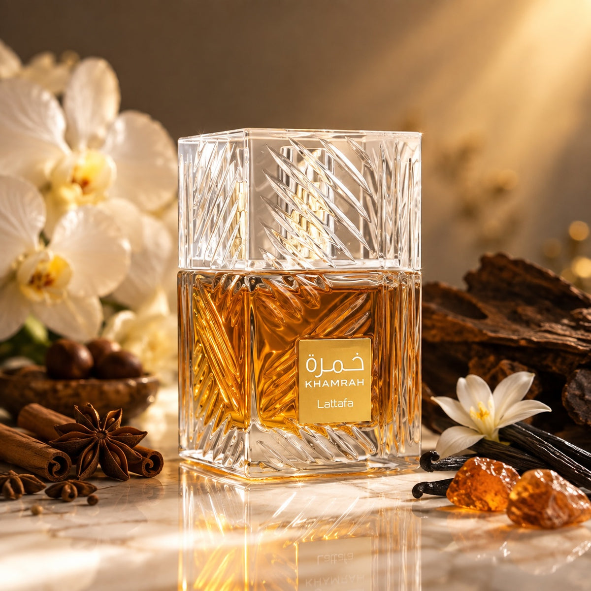 Noor Fragrances Lattafa Khamrah Eau de Parfum in a crystal bottle with cinnamon, vanilla, and amber on a marble table.