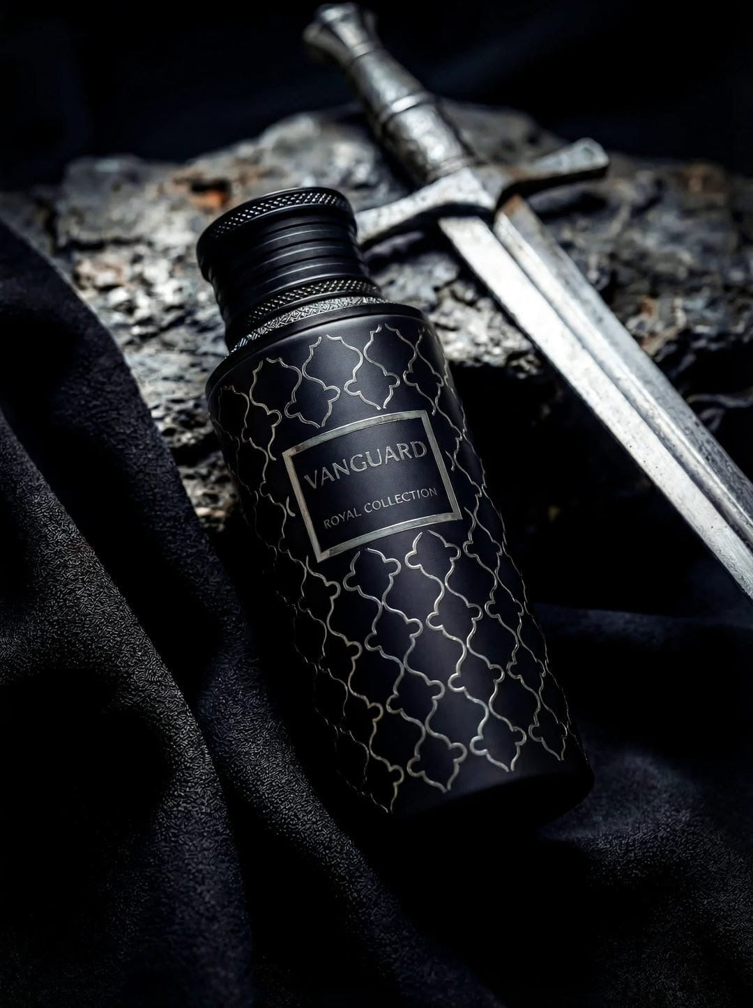 Noor Fragrances Vanguard Royal Collection perfume in a matte black bottle with silver geometric patterns next to a sword.